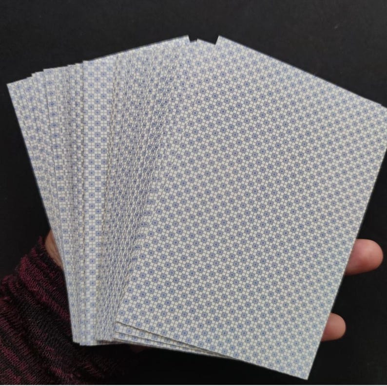 Dos des cartes du Grand Jeu de Mademoiselle Le Normand étalées dans une main, avec les tranches visibles.