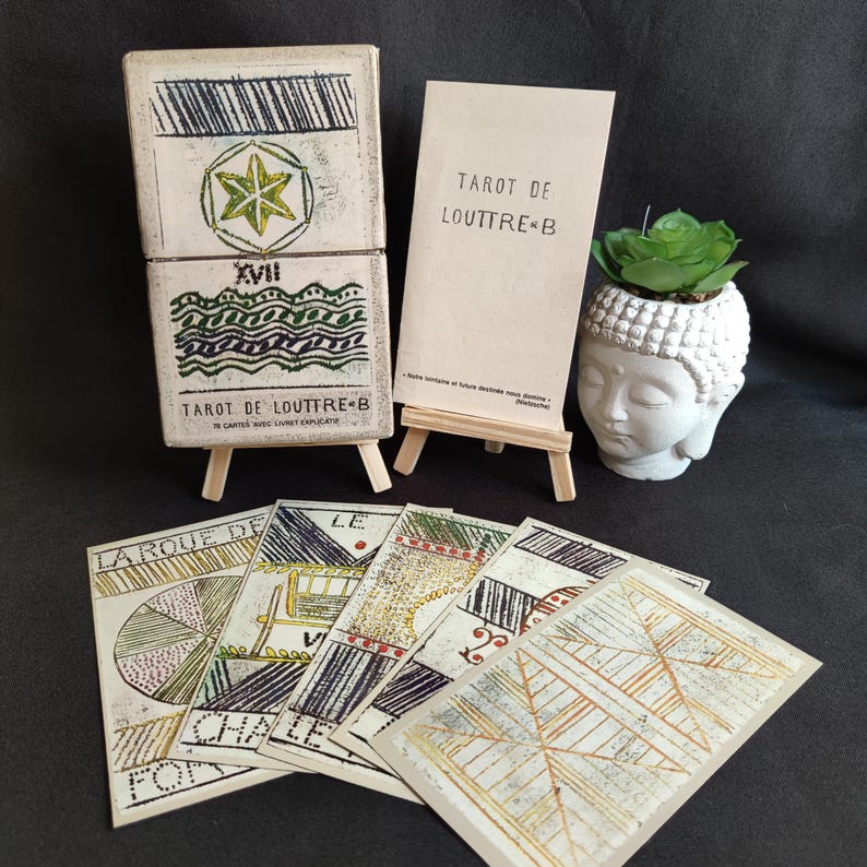 Tarot de Louttre B Grimaud de 1981 avec sa boîte d’origine, sa notice explicative et plusieurs cartes étalées.